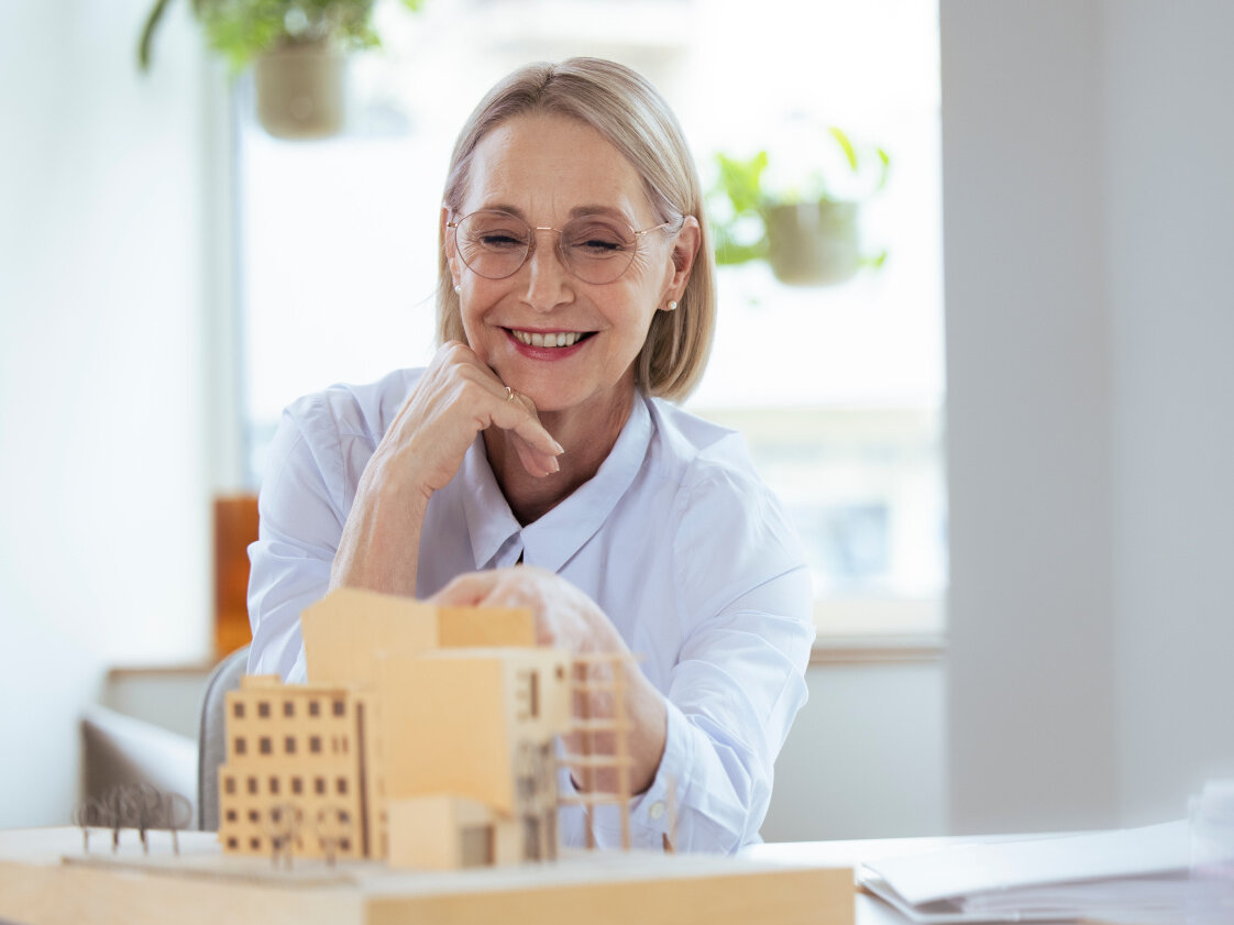 AdobeStock_472046452 Smiling businesswoman checking model at workplace