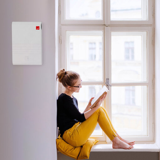 Zehnder_CSY_CA70_Milieu_YellowReading_Livingroom_Web A young happy college female student with a book sitting on window sill at home, studying.