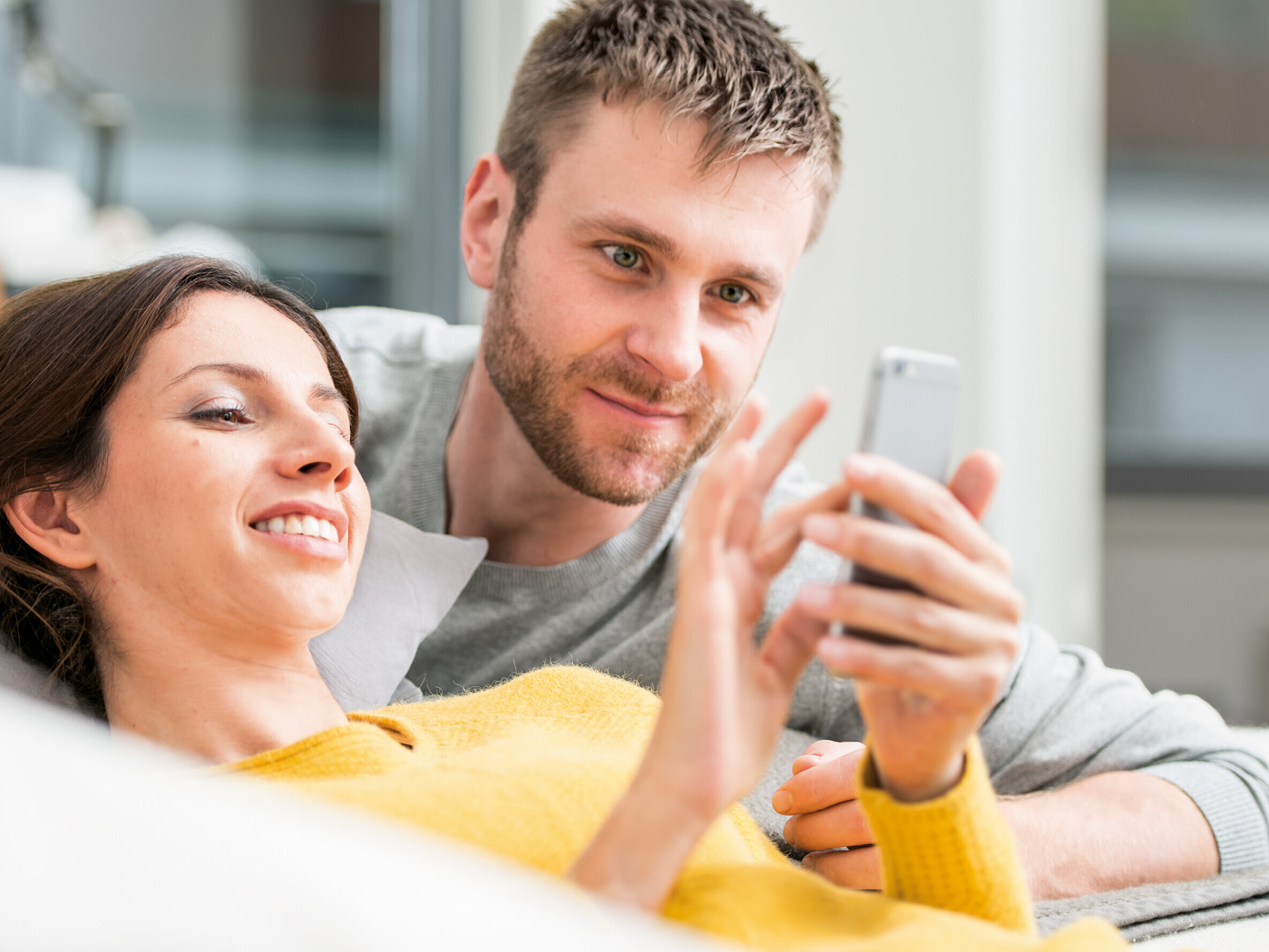Regolazione dell'aria ambiente tramite smartphone Donna con smartphone, sdraiata sul divano