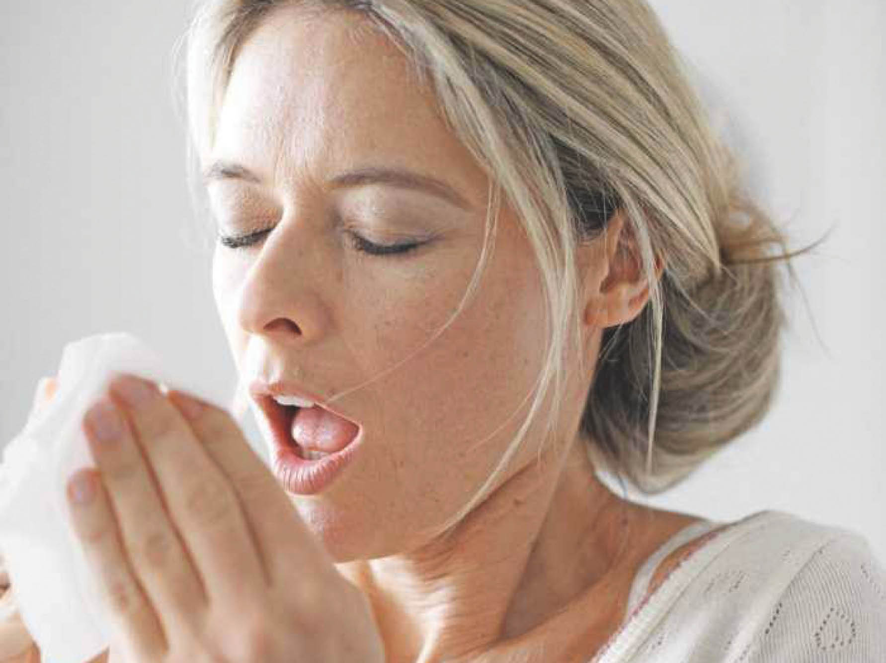 Une femme éternue à cause d'une allergie au pollen