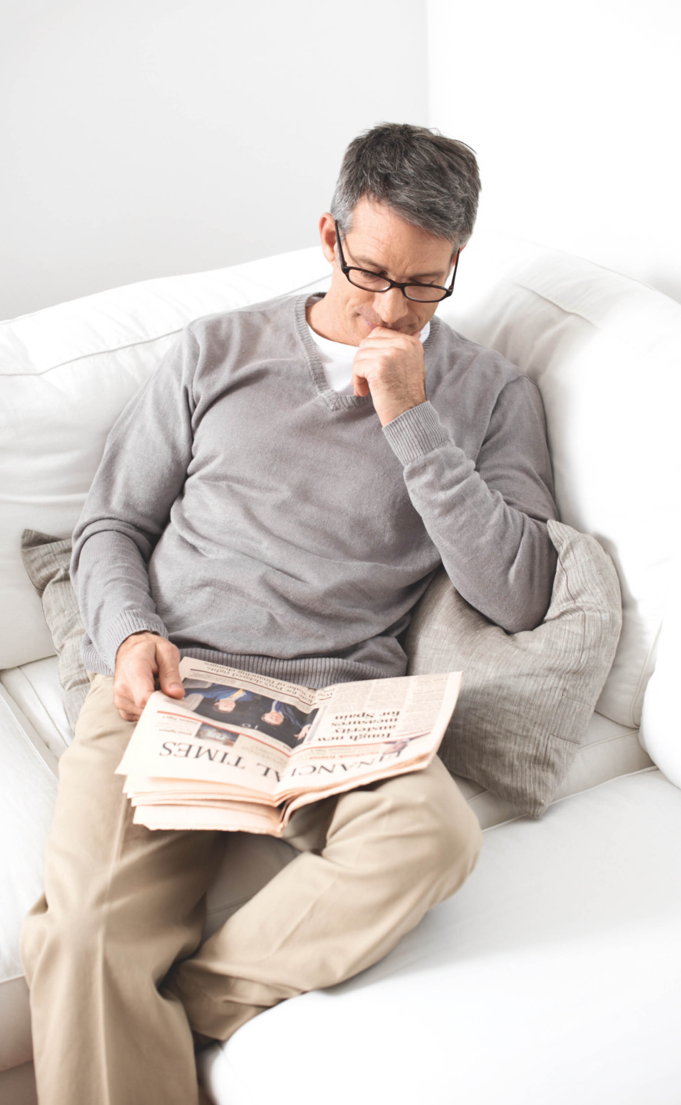 Mann liesst Zeitung auf Sofa